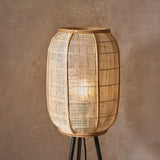 Daneshaw Floor Lamp with cylindrical natural linen and bamboo shade on a matt black tripod base, shown lit against a neutral background.