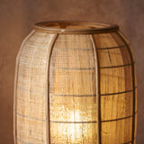 Daneshaw Floor Lamp close-up showing the woven natural linen shade over a bamboo frame with visible ribs, glowing warmly when lit.