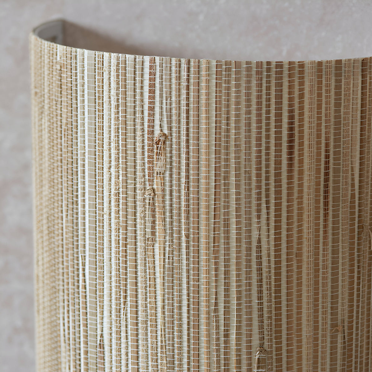 Close-up of the Endon Salcombe wall light showing the woven natural seagrass half-cylinder shade with visible vertical stripes and knotted fibres.