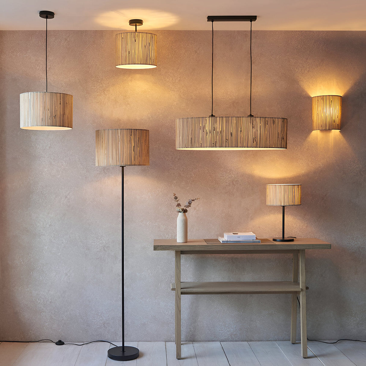 Salcombe Pendant Light in black and natural woven seagrass, shown with matching floor and table lamps and a wall light in a warm living room setting.