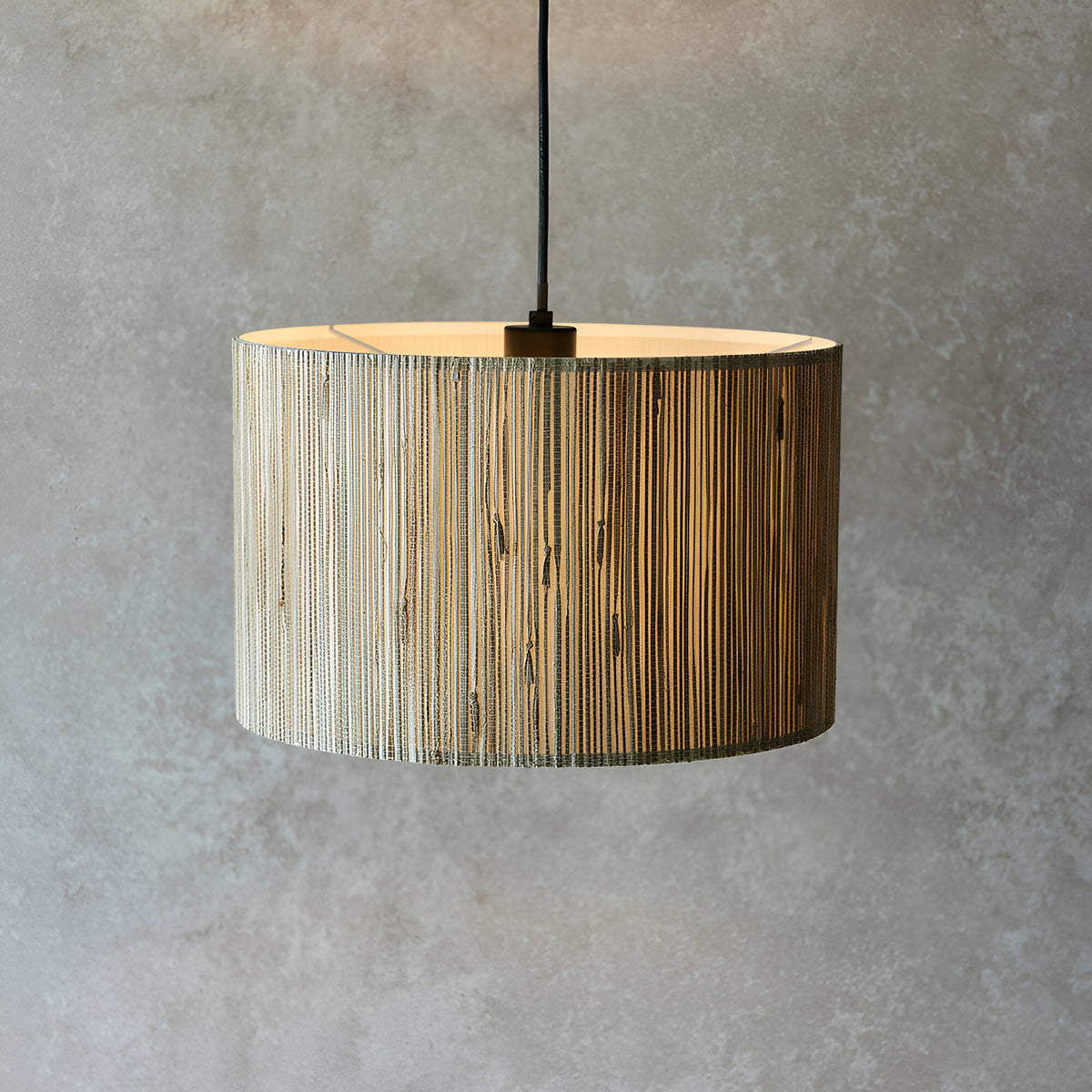 Salcombe Pendant Light in black and natural woven seagrass drum shade, single E27 fitting on black cable, shown against a grey textured background.