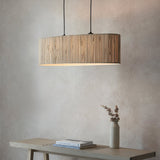 Endon Salcombe 2 light linear pendant with woven natural seagrass oval shade and matt black cables, hung above a wooden console with a vase.