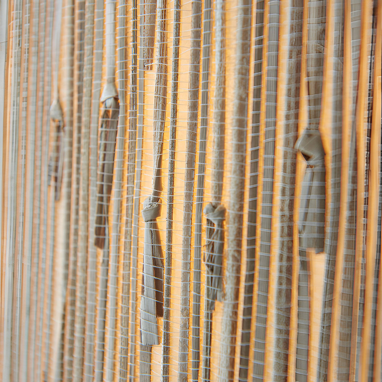 Close-up of the Endon Salcombe pendant's woven natural seagrass shade, showing the vertical grain lit with a warm glow.