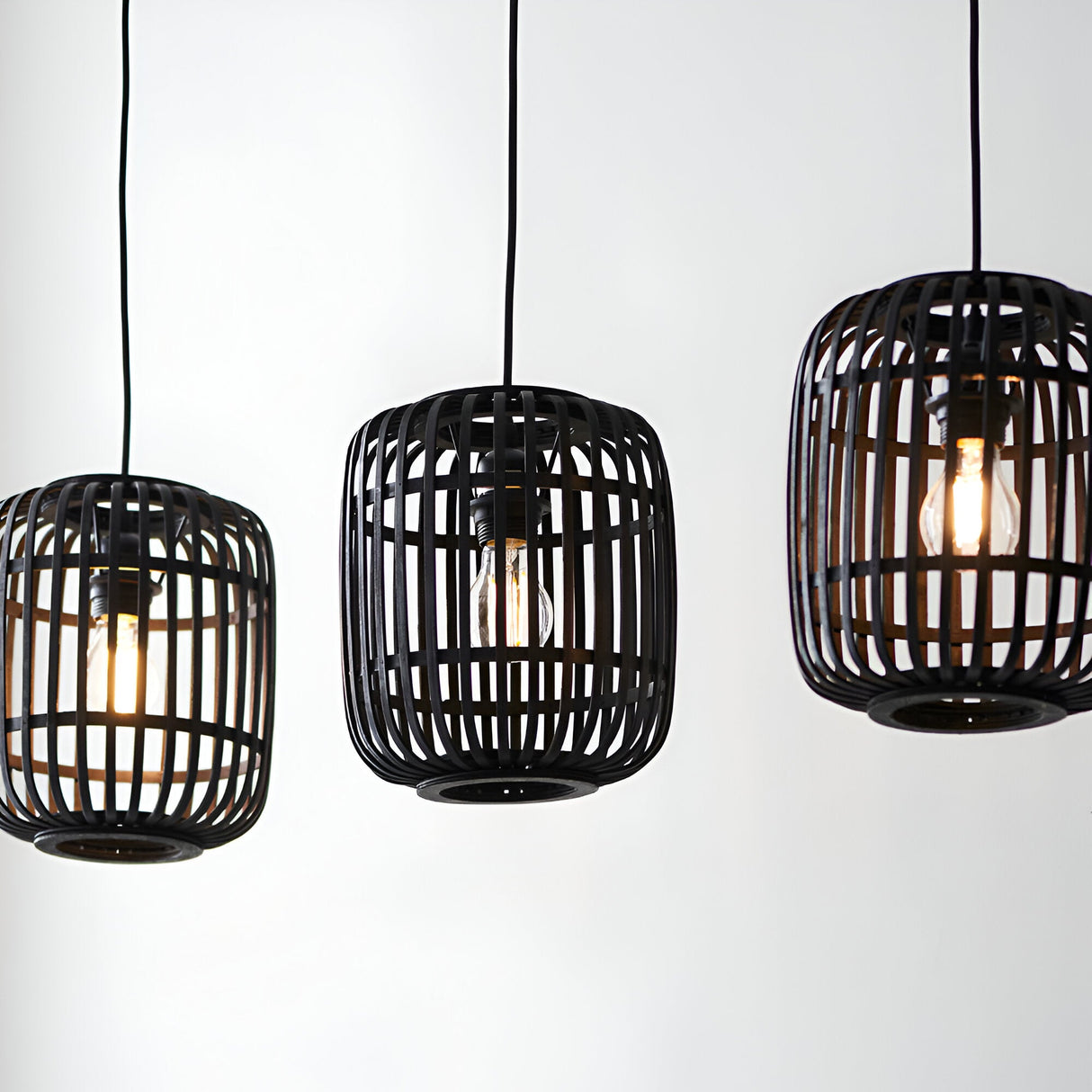 Endon Bracken 3 Light Pendant in black with three linear bamboo cage shades and exposed filament bulbs against a plain white background.