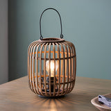 Endon Bracken table lamp with an open bamboo cage, matt black metal handle and exposed E27 filament bulb, shown lit on a wooden table.