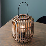 Endon Bracken table lamp with natural bamboo cage frame, matt black metalwork, arched handle and exposed filament E27 bulb, on a wooden table.