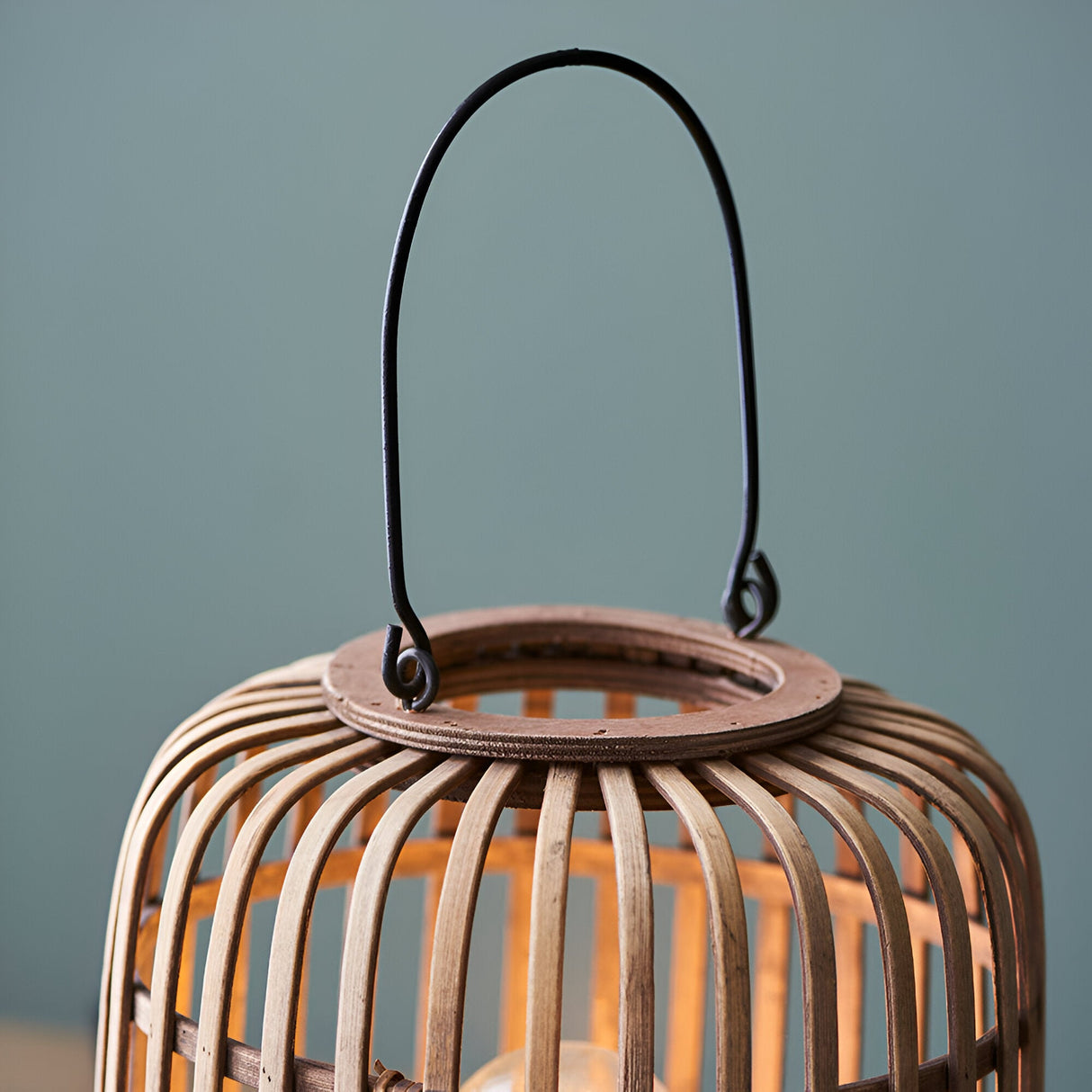 Endon Bracken table lamp close-up showing the natural bamboo cage top, matt black metal handle, and warm filament bulb glow inside.