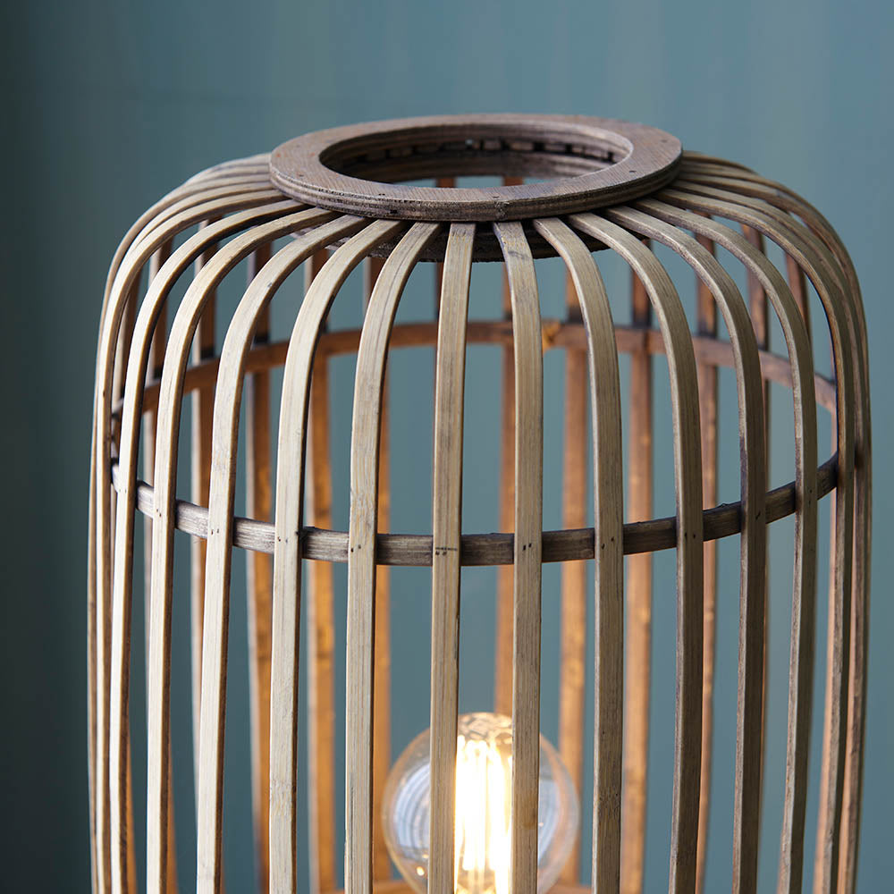 Bracken Floor Lamp close-up showing natural bamboo cage frame with dark wooden top ring and lit E27 bulb visible inside.