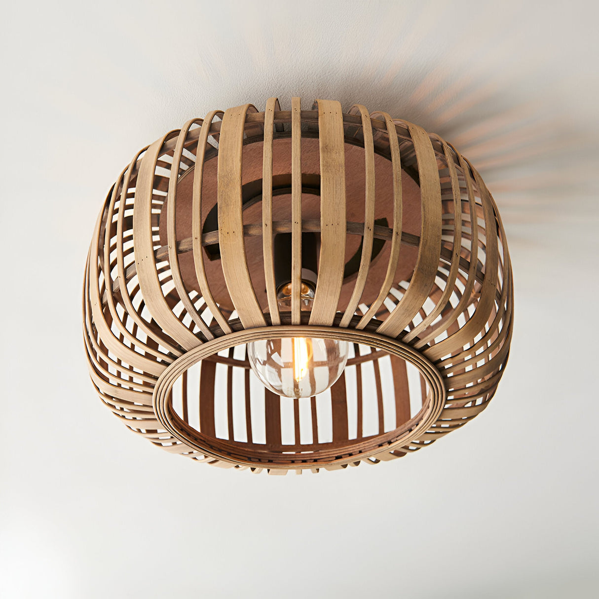 Endon Bracken bamboo flush ceiling light in a natural finish, with a rounded woven shade and single E27 lamp, mounted to a white ceiling.