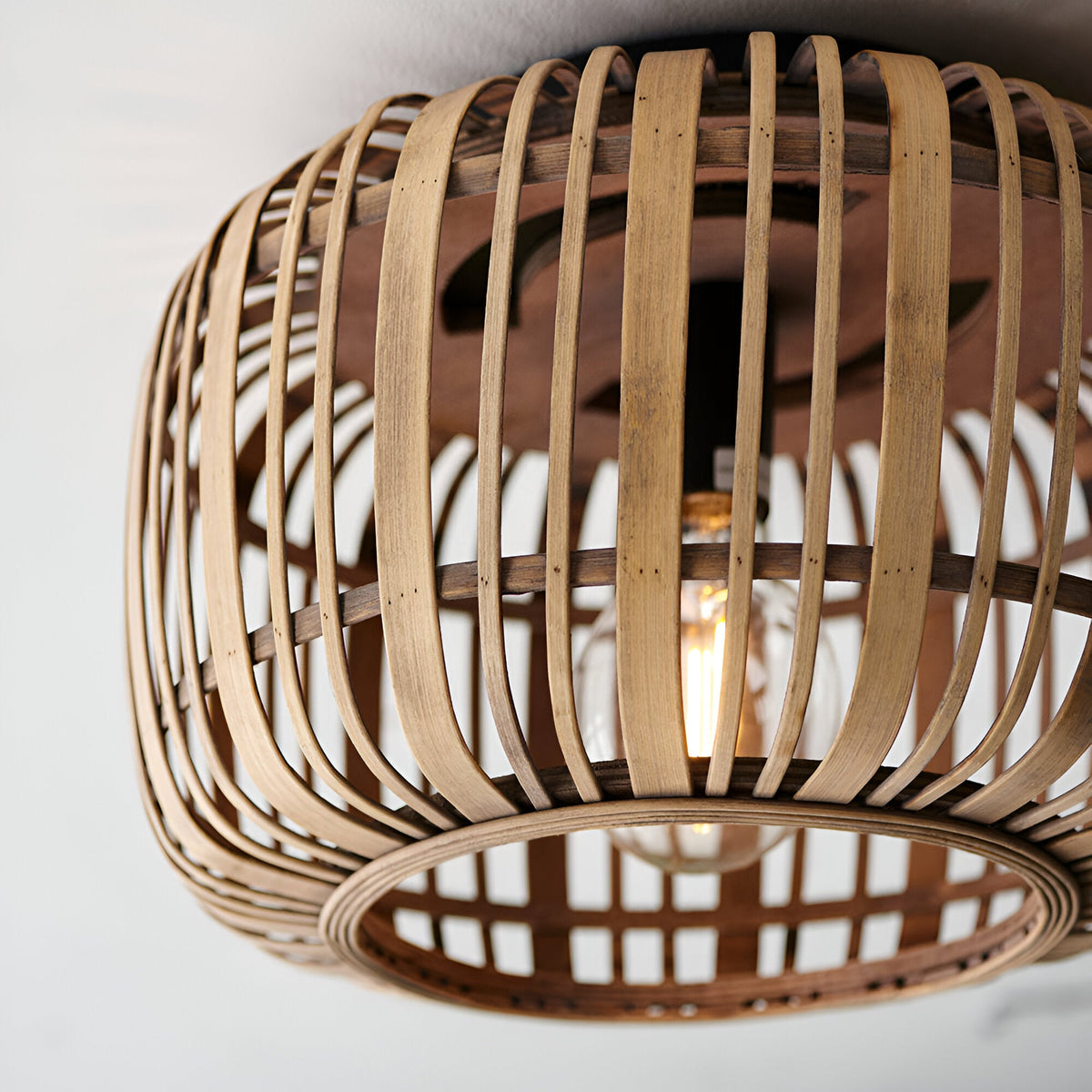 Endon Bracken bamboo flush ceiling light in a natural woven finish, shown close up with a single E27 lamp glowing inside the rounded shade.