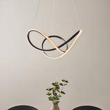 Bramcombe Pendant in black and white featuring interlocking matt black curves with faceted acrylic light strips, suspended above a dining table with a plant.