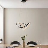 Bramcombe Pendant in matt black with clear faceted acrylic detail, sculptural looped design, hung above a dining table in a neutral-toned room.