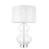 Endon Brockley table lamp with a clear glass hourglass base, polished nickel metalwork and a vintage white fabric drum shade, on a white background.