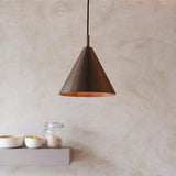 Endon Ashworth cone pendant light in brushed antique bronze with matching painted inner and black cable, hung above a shelf with bowls and a jar.