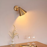 Endon Ashworth brass wall light with adjustable arm and cone shade, illuminating a dining setting with a glass vase and wine glasses below.
