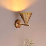 Endon Ashworth brass wall light with a conical shade on an adjustable arm, casting a warm glow on the wall above.