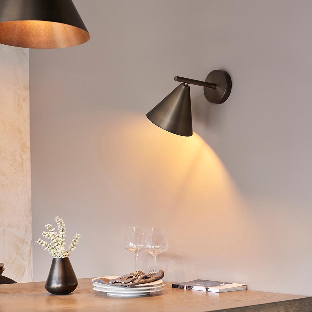 Endon Ashworth bronze wall light with adjustable arm and conical shade, illuminating a dining console with vase, glasses and plates.