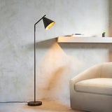 Ashworth Floor Lamp in bronze with adjustable arm and cone shade, shown beside a beige sofa and shelf in a living room.