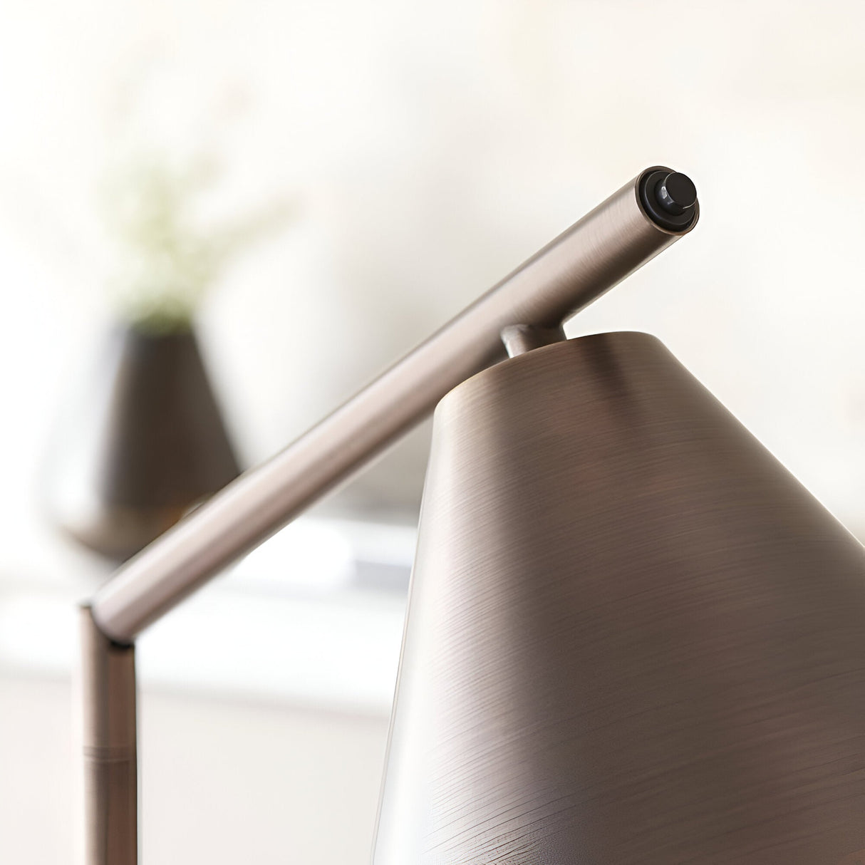 Close-up of the bronze Ashworth Floor Lamp showing the brushed metal cone shade, adjustable arm, and jointed hinge detail.