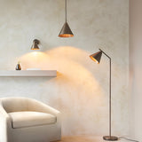 Ashworth Floor Lamp in bronze with adjustable arm and cone shade, shown beside a matching pendant and wall light in a living room setting.
