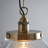 Wentworth Pendant in brass with knurled E27 lampholder, clear glass shade, visible filament bulb, hook and chain, on light grey background.
