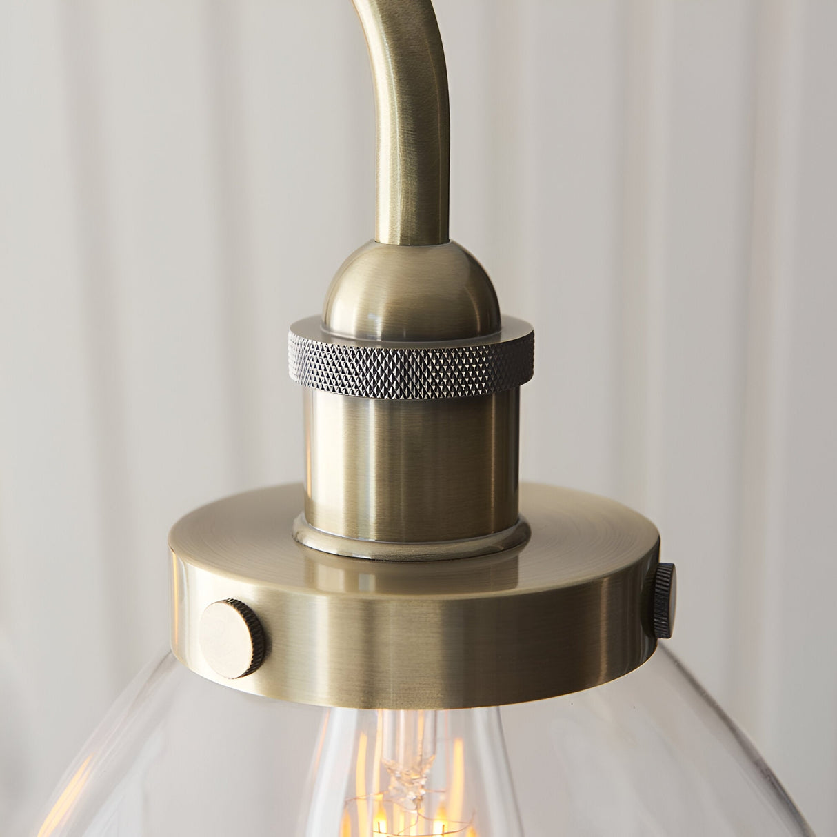 Close-up of Endon Wentworth pendant showing antique brass lamp holder with knurled detail, clear glass shade, and exposed E27 filament bulb.