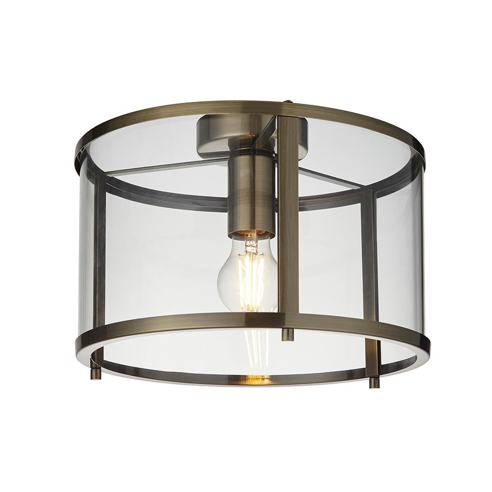 Endon Ellery flush ceiling light in brass with a cylindrical clear glass shade and single E27 exposed filament bulb, shown on a plain white background.