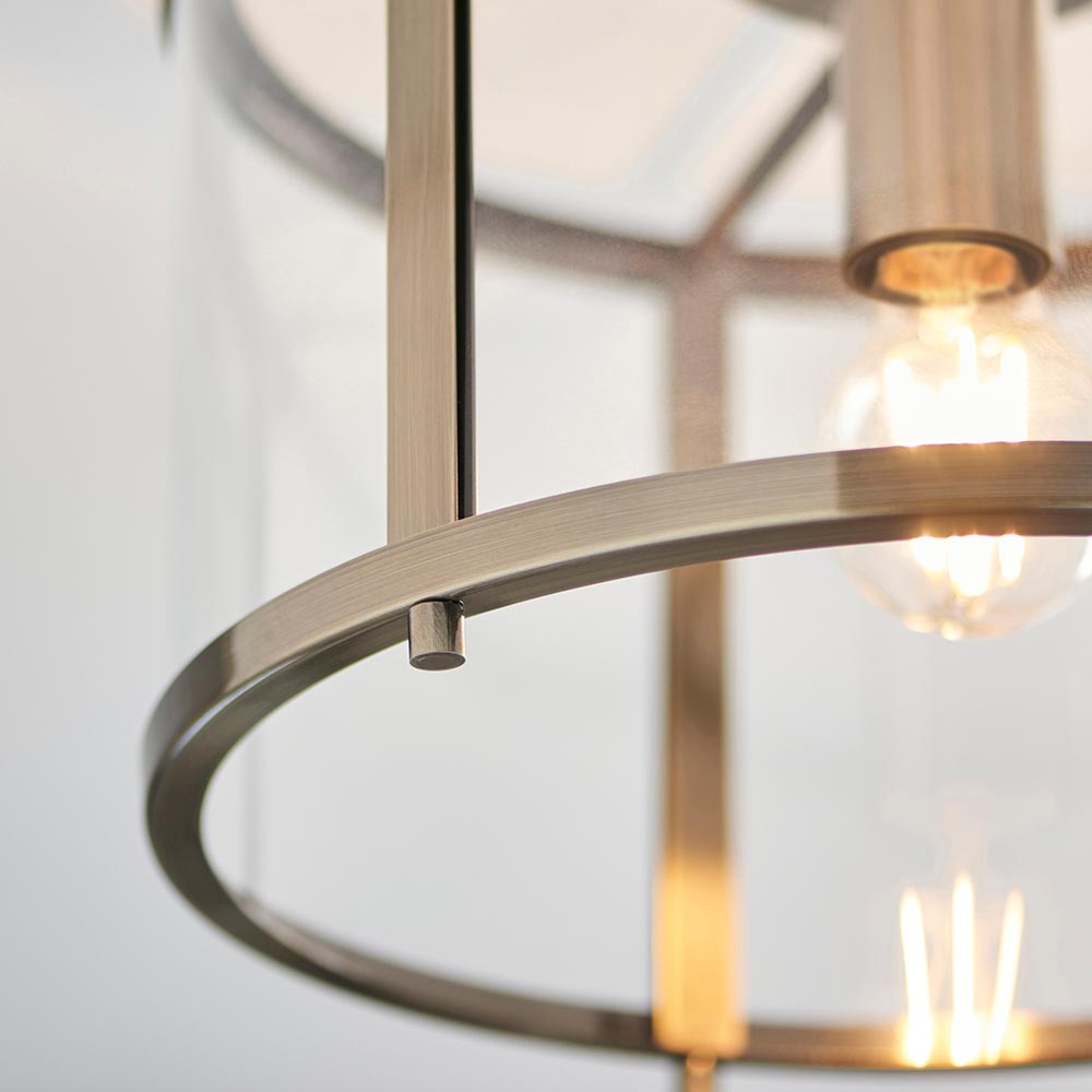 Close-up of Endon Ellery flush ceiling light in brass, showing the curved metal frame ring, central stem and illuminated E27 bulb behind glass.