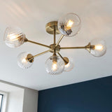 Endon Georgiana 6 light semi-flush ceiling light in brass, with six ribbed clear glass globe shades on angled arms around a central plate.