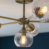 Close-up of Endon Georgiana 6 light semi-flush ceiling light in brass, showing ribbed glass globe shades and slender arms radiating from a central plate.
