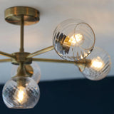 Endon Georgiana 6 light semi-flush ceiling light in brass, with ribbed glass globe shades arranged around a central plate, shown from below.