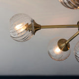 Endon Georgiana semi-flush ceiling light shown close-up with brass arms and swirled glass globe shades lit against a pale ceiling.