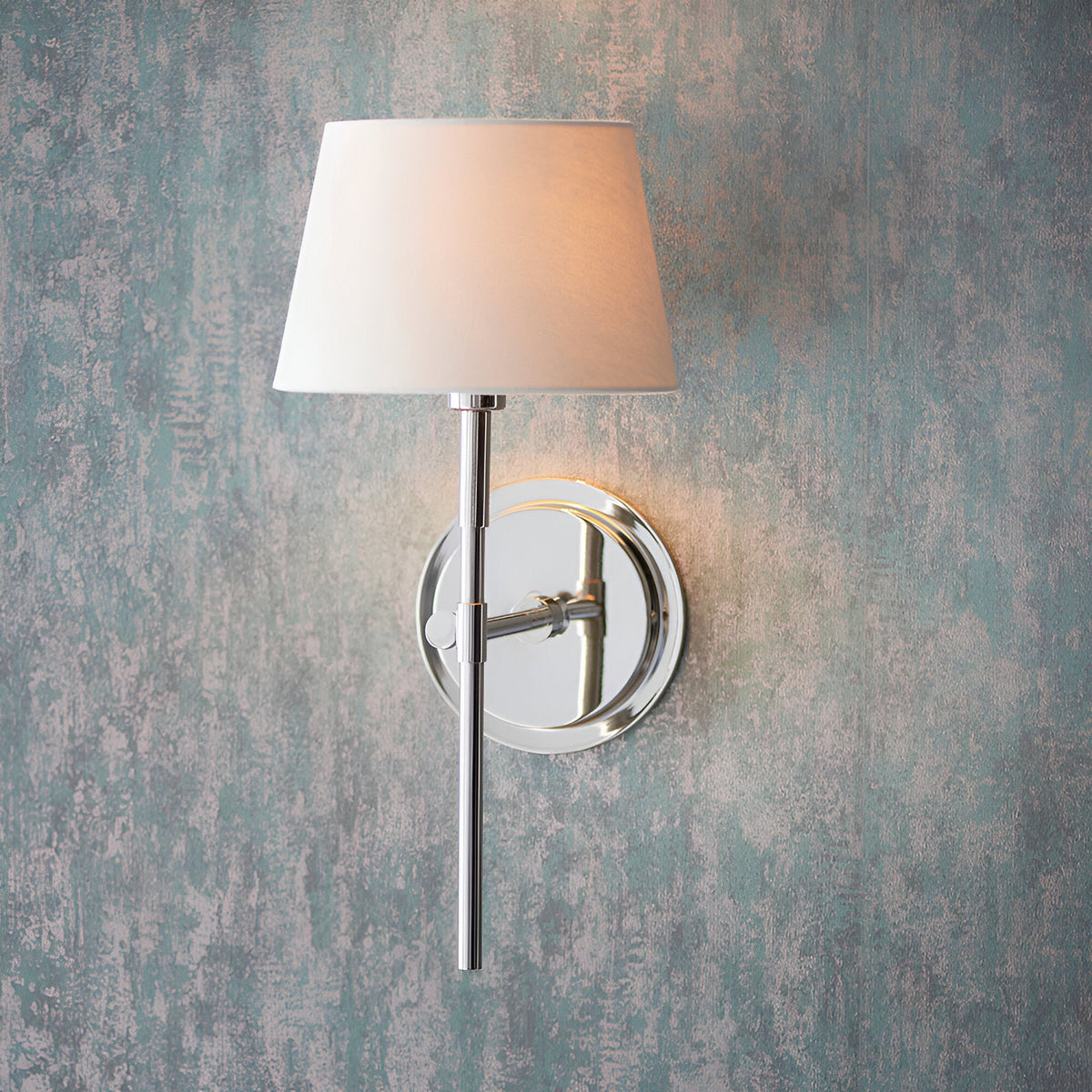 Endon Chartwell wall light with slim nickel bracket and tapered ivory fabric shade, illuminated against a distressed blue-grey wall.