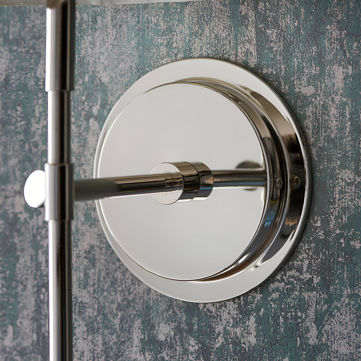 Close-up of Endon Chartwell wall light backplate and slim arm in polished nickel, mounted on a textured teal wall.