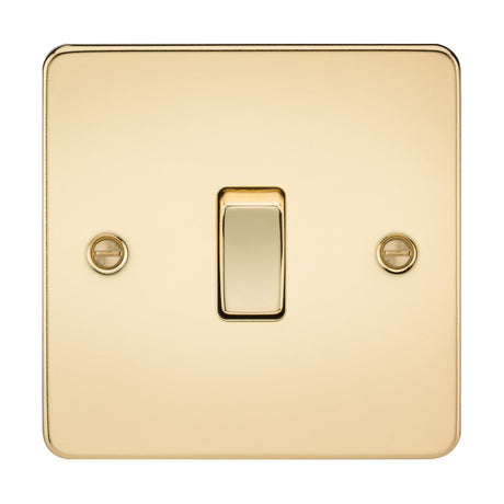 A 10AX 1 Gang Intermediate Switch in polished brass with a flat plate, mounted on a wall. It features a centered single toggle switch and two visible screws for securing the plate, showcasing its shiny, reflective surface and low-profile design.