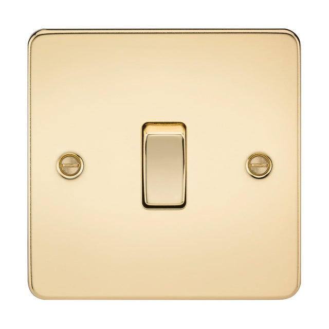 A 10AX 1 Gang Intermediate Switch in polished brass with a flat plate, mounted on a wall. It features a centered single toggle switch and two visible screws for securing the plate, showcasing its shiny, reflective surface and low-profile design.