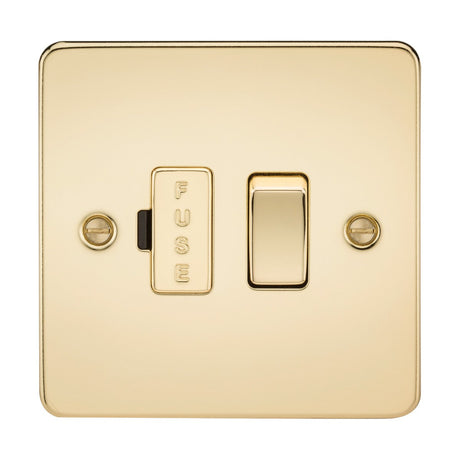 A polished brass 13A switched fused spur unit, featuring an ultra-low profile flat plate design, is set against a white background and includes a toggle switch. Two screws are visible on either side of the gleaming plate.