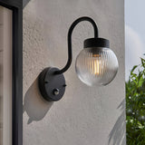 Endon Brackgrove outdoor wall light in black with arched arm, ribbed clear glass globe shade and PIR sensor, mounted on a rendered exterior wall.
