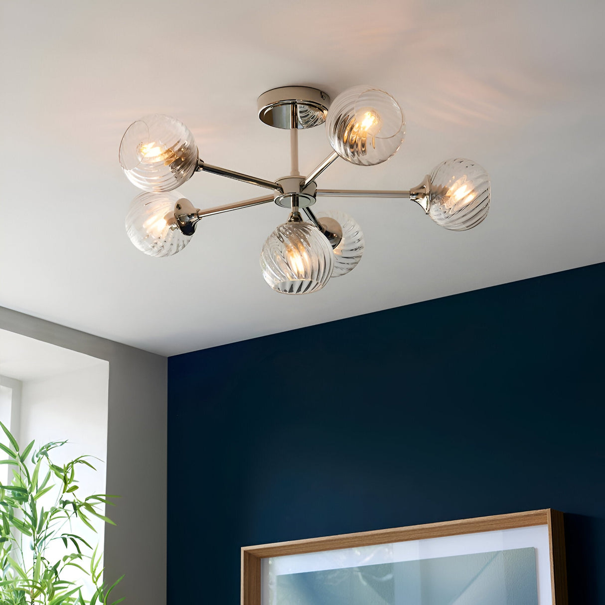 Georgiana 6 Light Semi-Flush Ceiling Light in nickel, sputnik-style arms with six ribbed glass globe shades, fitted on a dark blue wall room ceiling.