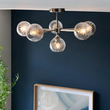 Georgiana 6 Light Semi-Flush Ceiling Light in nickel with ribbed globe glass shades, shown in a room with a dark blue wall and framed artwork below.