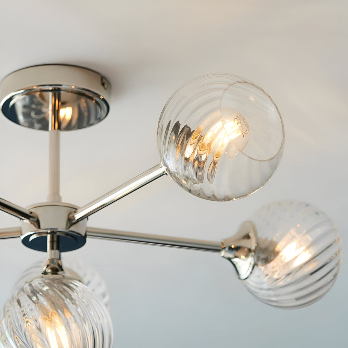 Georgiana 6 Light Semi-Flush Ceiling Light in nickel, close-up of ribbed globe glass shades on angled arms from a central plate, lit bulbs visible.