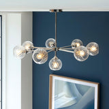 Endon Georgiana 8 light pendant in nickel with spiral-cut clear glass globes on a semi-flush metal frame, shown lit against a dark blue wall.