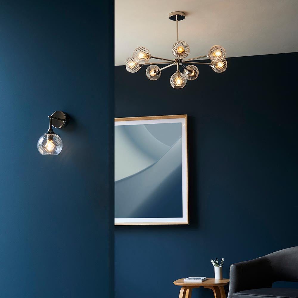 Endon Georgiana 8 light semi-flush pendant in nickel with spiral clear glass globes, lit above a framed mirror on a deep blue wall.