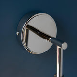 Close-up of the Endon Georgiana wall light's round nickel backplate mounted on a deep blue wall, with the polished arm extending outward.