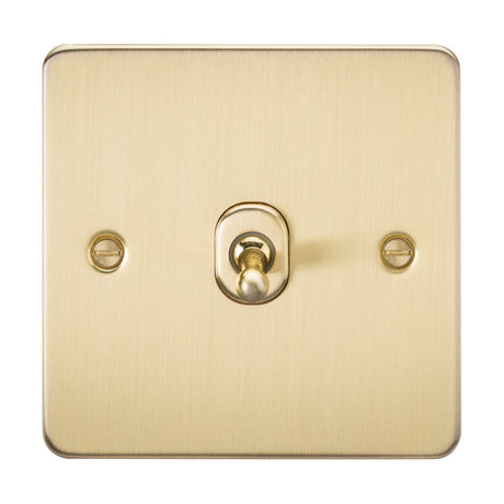The 10AX 1 Gang Intermediate Toggle Switch - Brushed Brass (Flat Plate) features a simple, stylish design with a centered square switch and two visible screws, showcasing the metallic texture and tone for both style and functionality.