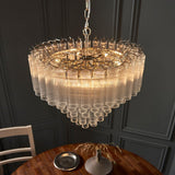 Endon Cranshaw 12 light tiered pendant in polished chrome with layered ribbed clear glass tubes, suspended by chain above a wooden dining table.