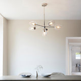 Endon Caldworth 6 Light Pendant in nickel with slender curved arms and clear blown glass shades, hanging above a dining table in a neutral room.