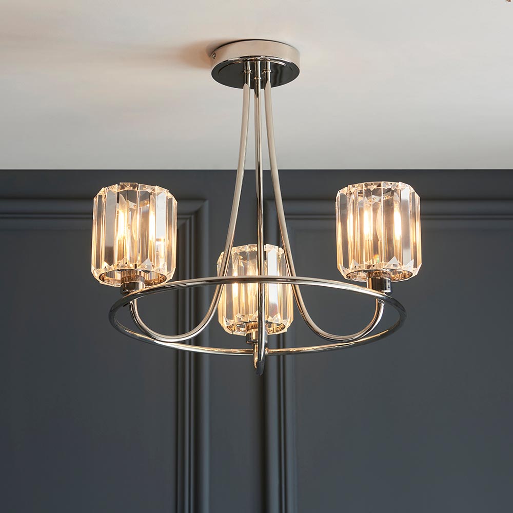 Clementine 3 Light Semi-Flush Ceiling Light in nickel with three crystal glass shades, curved arms and round ceiling plate, shown against a dark panelled wall.