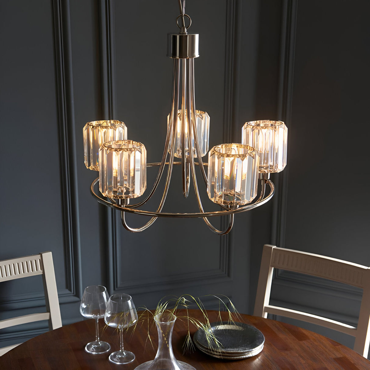 Clementine 5 Light Pendant in nickel with five cut faceted glass shades on curved arms, hung above a dining table in a dark-panelled room.