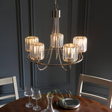 Clementine 5 Light Pendant in nickel with five cut faceted glass shades on curved arms, hung above a dining table in a dark-panelled room.